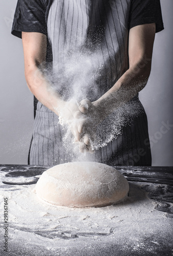 Posypywanie ciasta bochenka chleba mąką osoba w fartuchu piekarz