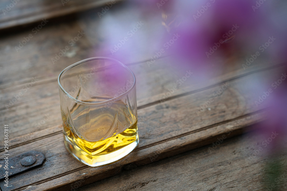 Glass of scotch whisky on rustic wooden barrel with reflections