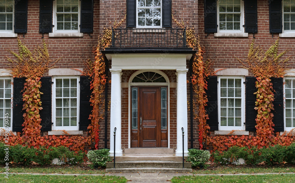 Traditional two story brick house with colorful ivy in fall. Stock