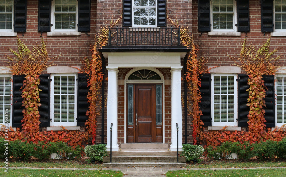 Traditional two story brick house with colorful ivy in fall.