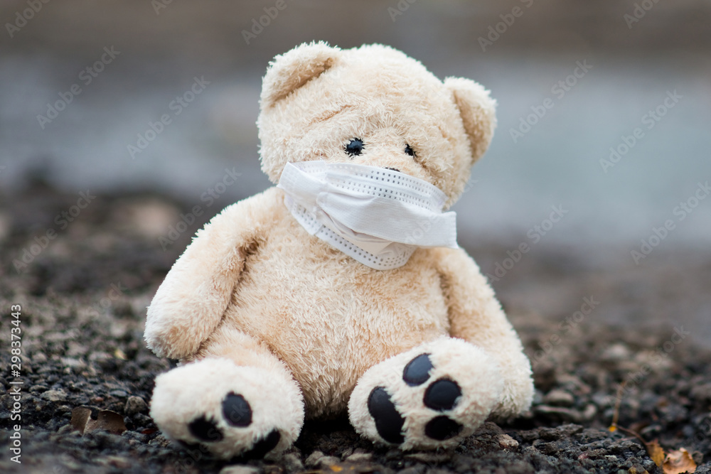 A teddy bear in a protective medical bandage sits on dirty soil, symbolizing a dangerous habitat A teddy bear in a protective medical bandage sits on dirty soil, symbolizing a dangerous habitat