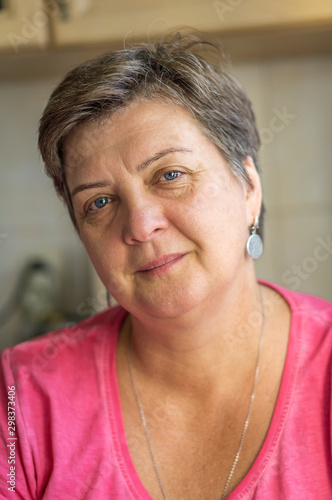 Mature woman in red sitting by the window, smiling