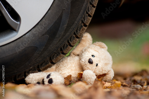 A teddy bear under the wheel of a car photo