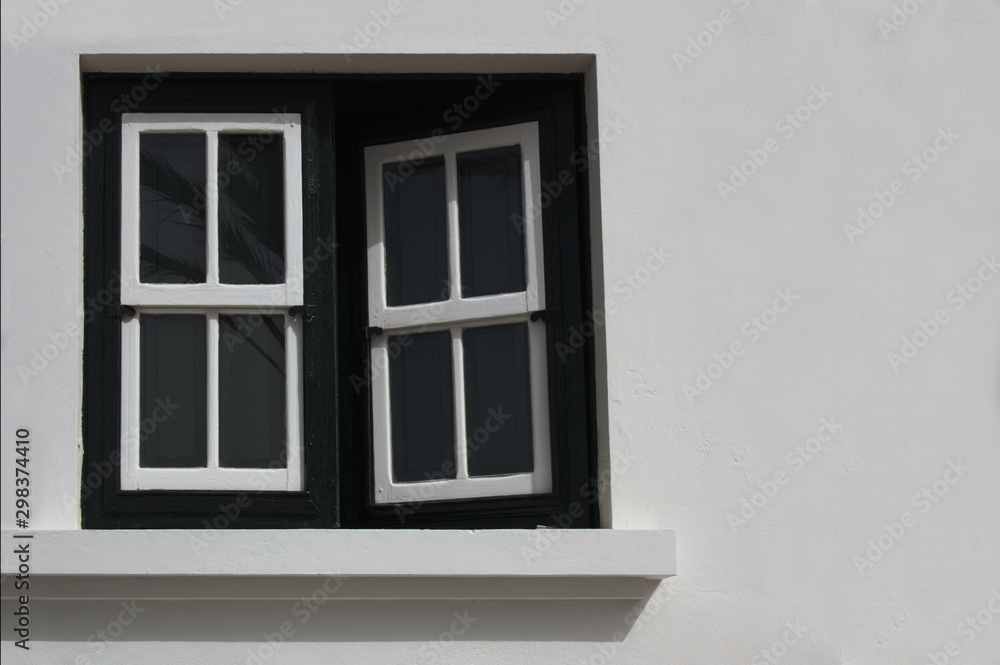 A half-open wooden and glass window in a white exterior wall