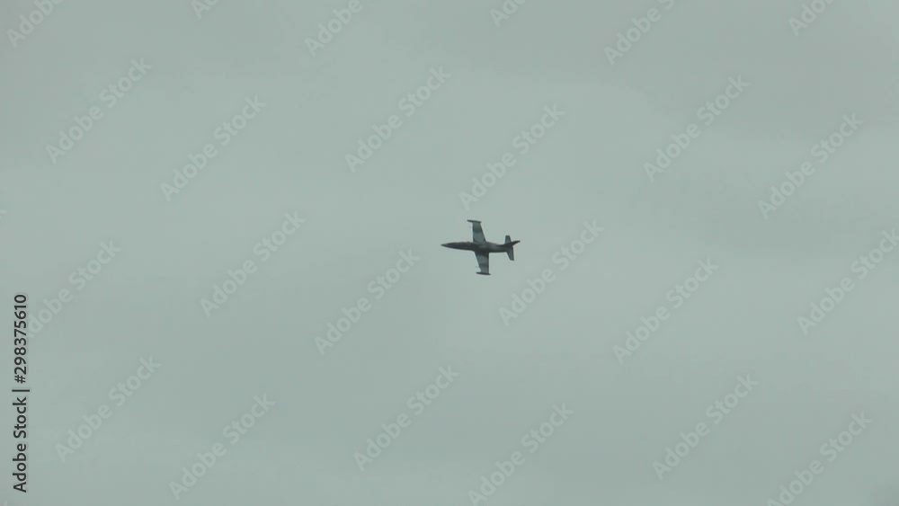 A gray blue combat fighter plane fly quickly and low in air, turn left and going to strike against a cloudy overcast sky. War concept. View from the ground. A gray blue combat fighter plane fly quickly and low in air, turn left and going to strike against a cloudy overcast sky. War concept. View from the ground.