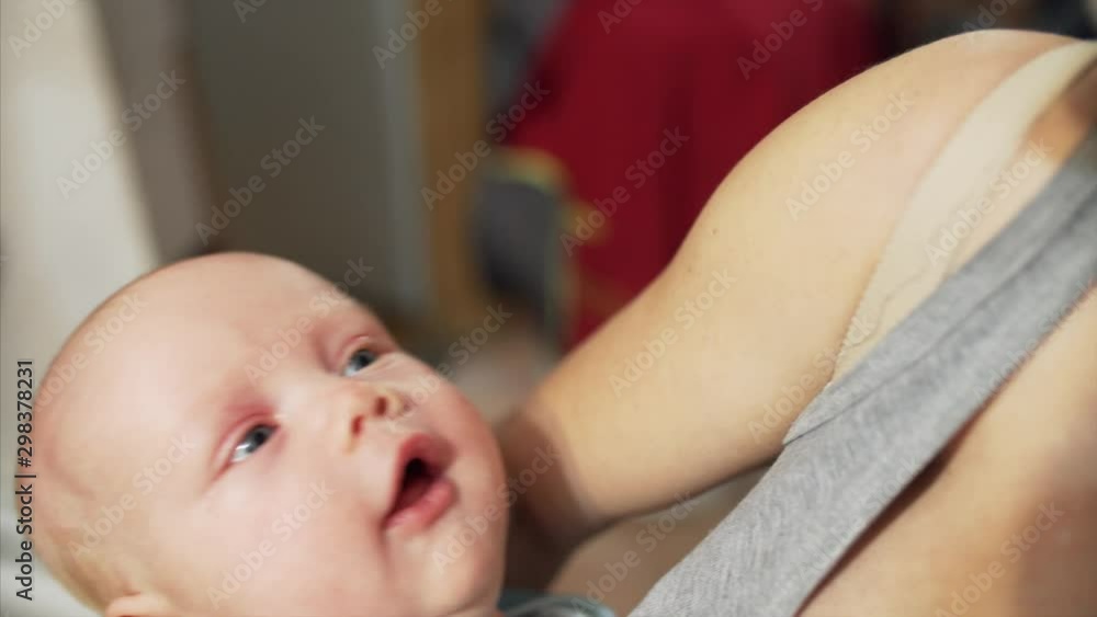 Happy unrecognized mother is holding her newborn son in her arms. Happy boy is smiling and looking at his mother Happy unrecognized mother is holding her newborn son in her arms. Happy boy is smiling and looking at his mother