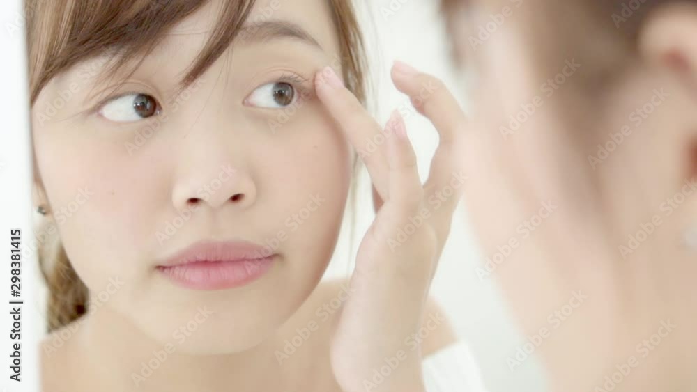 Beauty portrait young asian woman smiling look at mirror of checking skin care caucasian with wellness in the bedroom, beautiful girl happy face for health, lifestyle and wellbeing concept. Beauty portrait young asian woman smiling look at mirror of checking skin care caucasian with wellness in the bedroom, beautiful girl happy face for health, lifestyle and wellbeing concept.