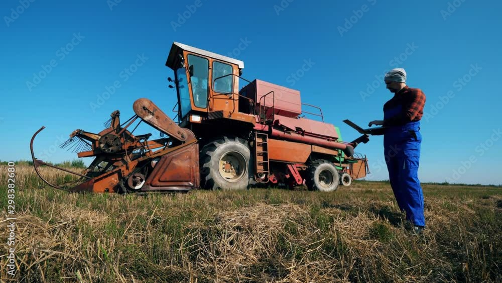 Combine vehicle and an agriscientist walking around it Combine vehicle and an agriscientist walking around it