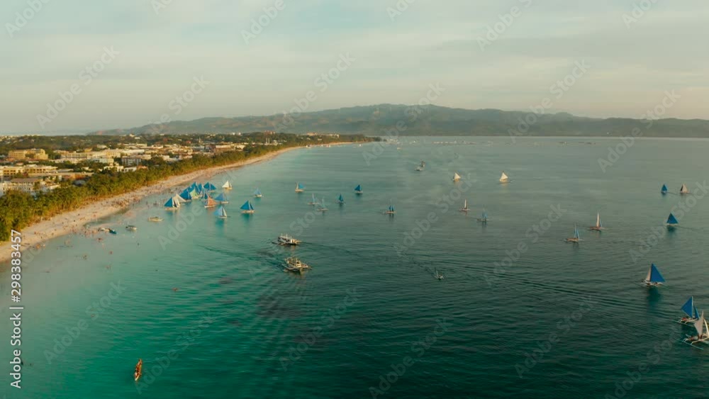 Tropical white beach from above at sunset with tourists and hotels and sailing boats on Boracay Island. Tropical white beach with sailing boat. Summer and travel vacation concept. Tropical white beach from above at sunset with tourists and hotels and sailing boats on Boracay Island. Tropical white beach with sailing boat. Summer and travel vacation concept.
