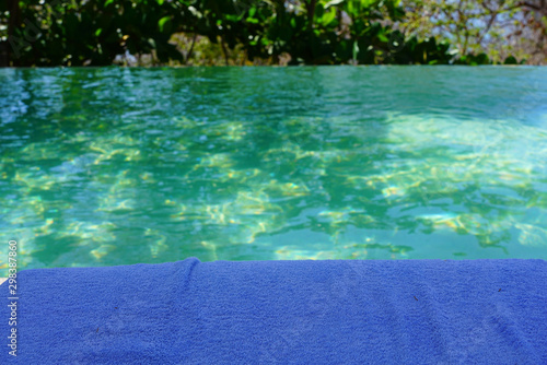 A lue beach towel by a turquoise swimming pool
