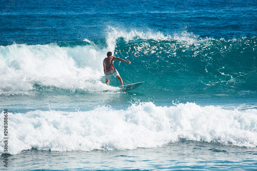 Surfer dressed in board shorts rides at high speed on a wave. Surfer dressed in board shorts rides at high speed on a wave.