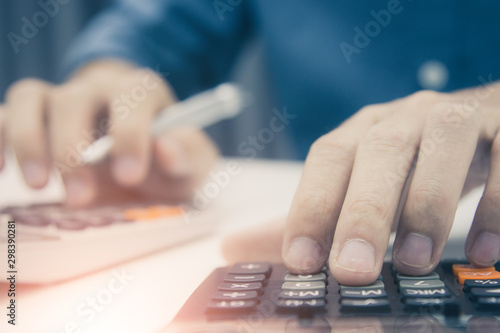 Close up man hand using calculator and writing make note with calculate about cost at sale office. © weerachai