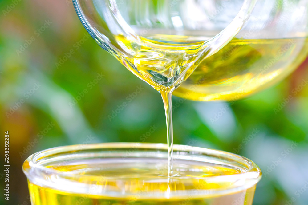 Pouring olive oil in the a glass bowl at stone kitchen and inside green garden view. Prepare for cooking concept. Healthcare and Beauty Concept. Pouring olive oil in the a glass bowl at stone kitchen and inside green garden view. Prepare for cooking concept. Healthcare and Beauty Concept.