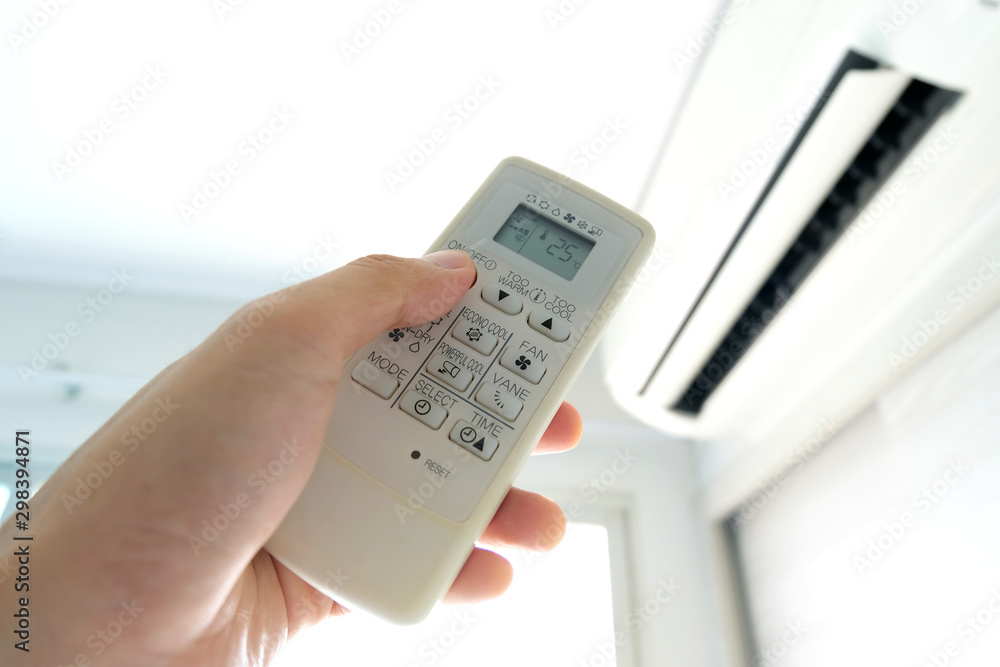 Man's hand using remote control open The air conditioner is cooled to 25 degrees Celsius in his bedroom. Health concepts and energy savings Man's hand using remote control open The air conditioner is cooled to 25 degrees Celsius in his bedroom. Health concepts and energy savings