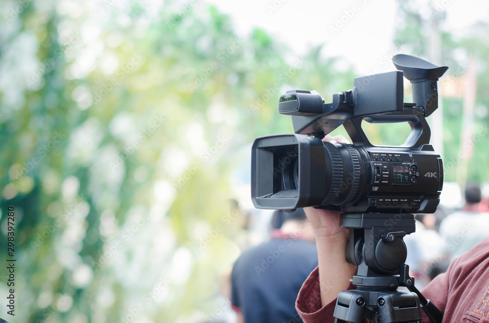 Professional video man hand holding Video camera operator camcorder working with his equipment outdoor with blurred background,copyspace