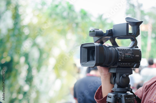Professional video man hand holding Video camera operator camcorder working with his equipment outdoor with blurred background,copyspace