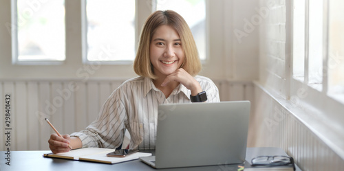 Young businesswoman working on her project with laptop computer and smiling to the camera