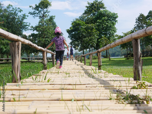 Asian baby girl walking to her mother and younger sister who were standing and waiting for her on a bamboo wooden pavement - family means no one gets left behind or forgotten