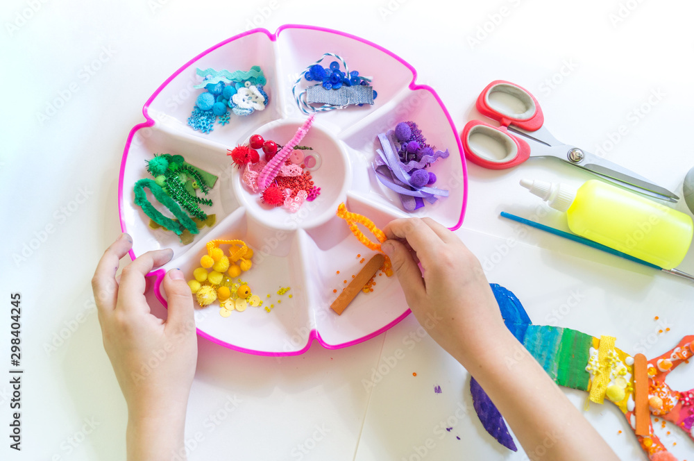 Fototapeta premium Hands of a child make a chameleon from cardboard. Rainbow color