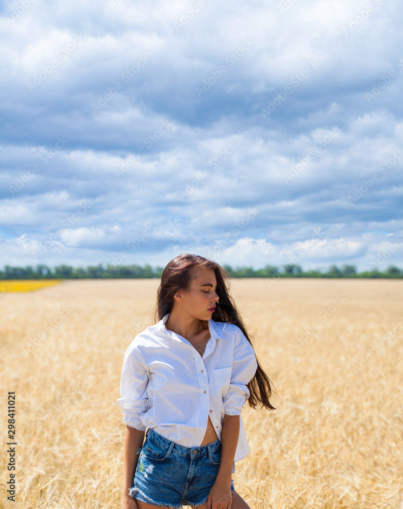 Young brunette woman in a white shirt and jeans shorts Young brunette woman in a white shirt and jeans shorts