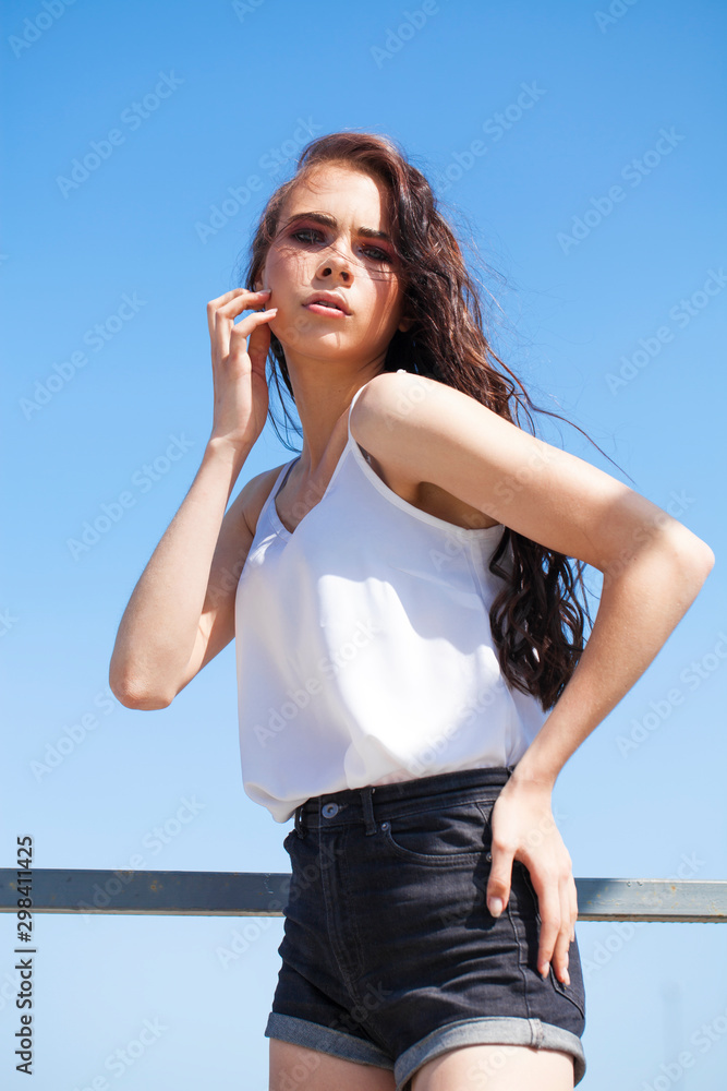 Pretty young brunette model in white summer blouse and jeans, summer street outdoors Pretty young brunette model in white summer blouse and jeans, summer street outdoors