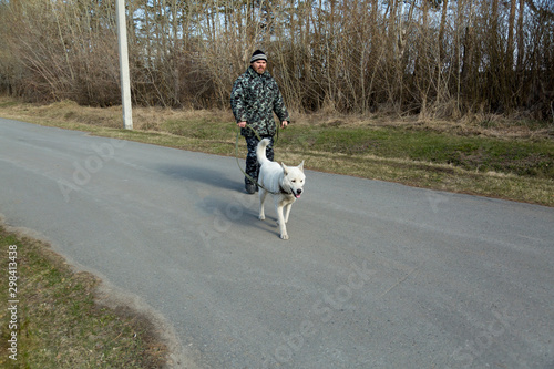 A man in overalls for a walk with a dog