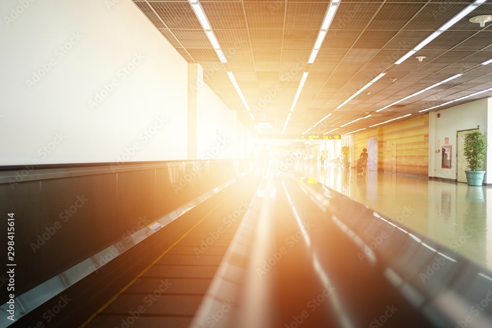 Moving horizontal walkway escalator (travelator/sidewalk) in international airport terminal in the morning with sunlight.