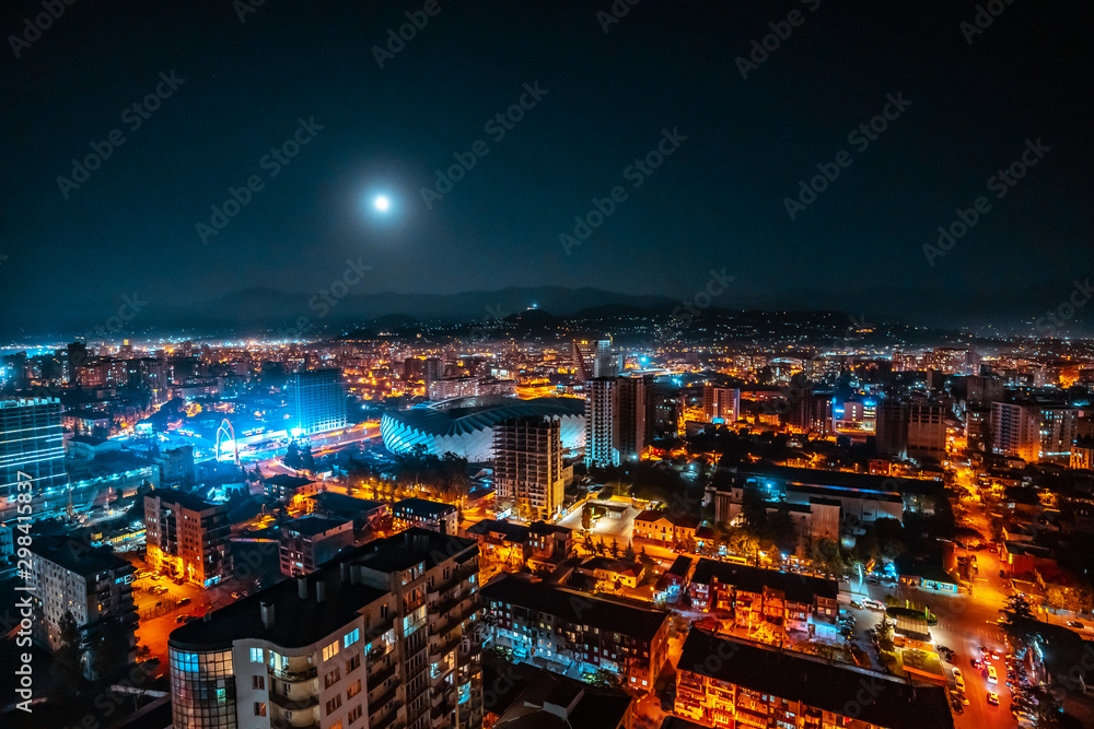 Panorama of a luminous night city illuminated by a bright moon