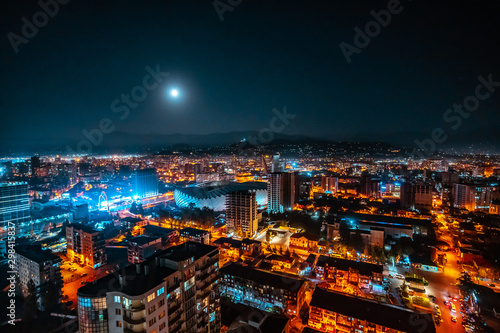 Panorama of a luminous night city illuminated by a bright moon