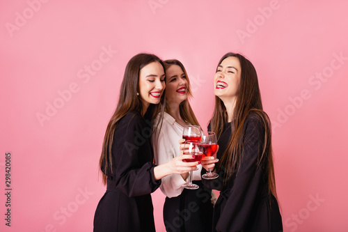 Three women celebrate hen-party having fun laughing and drinking wine.