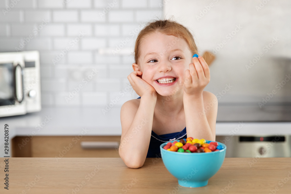 Happy little girl looking at candy in her hand Happy little girl looking at candy in her hand