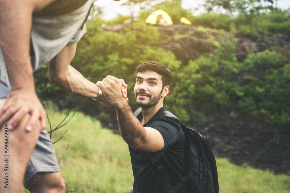 Backpackers man getting help to friend climb,Helping hand,Overcoming obstacle concept