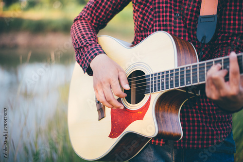 Music in nature  Man playing an acoustic guitar in meadow  Close-up  Copy-space