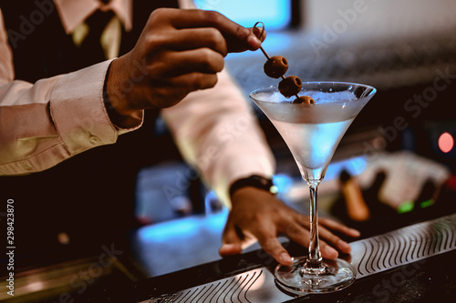 Billede på lærred The young bartender is making a cocktail and decorating it in a martini cocktail glass for beautiful at a nightclub bar