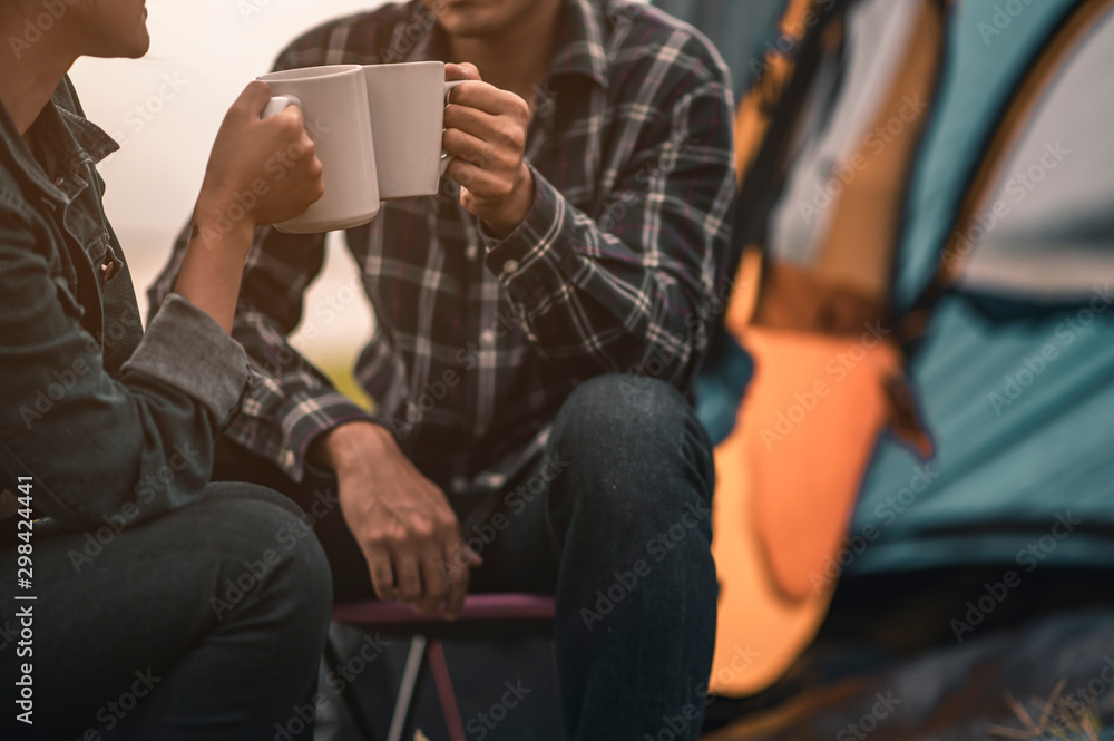 Male and female travelers are sitting and enjoying a drink after a set up outdoor tents on the riverfront during sunset. Male and female travelers are sitting and enjoying a drink after a set up outdoor tents on the riverfront during sunset.