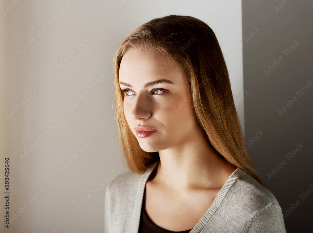 Dreaming woman standing near window in sunbeams. Portrait of blond woman. Dreaming woman standing near window in sunbeams. Portrait of blond woman.