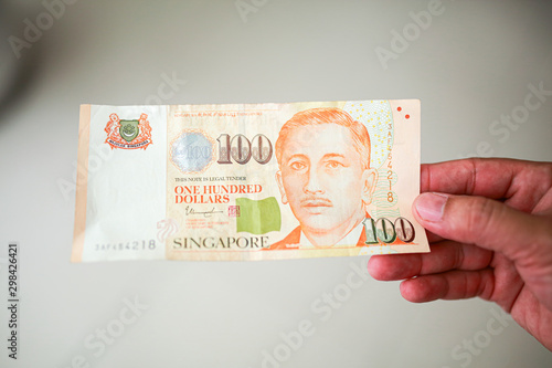 Wallpaper Mural Hand hold a 100 singapore dollar banknote ready for shopping, Singapore currency many value in shopping. Torontodigital.ca