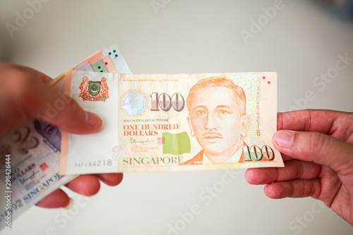 Wallpaper Mural Hand hold a 100 singapore dollar banknote ready for shopping, Singapore currency many value in shopping. Torontodigital.ca