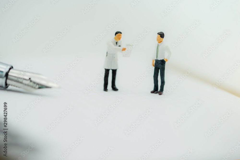 miniature people standing with fountain pen on paper with white background. miniature people standing with fountain pen on paper with white background.