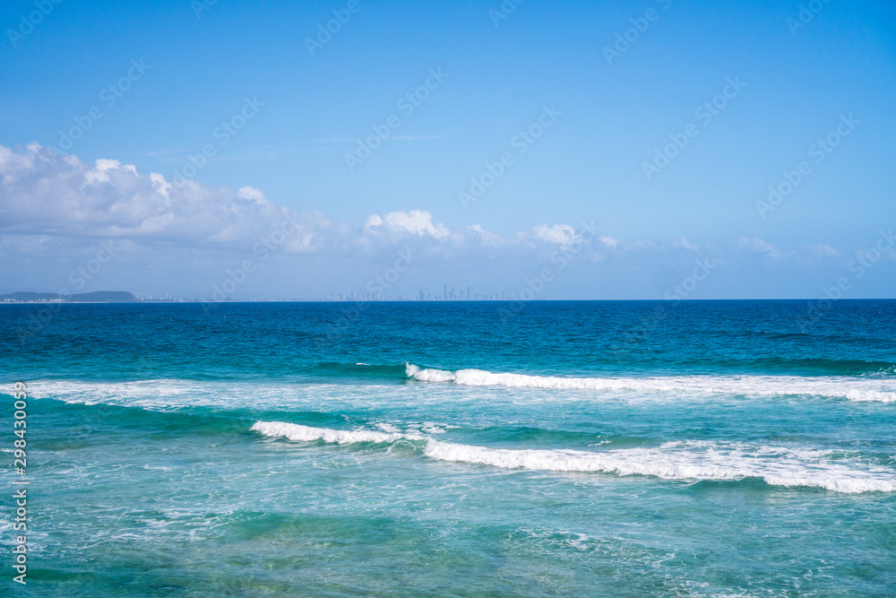 Stunning wide panorama of the Rainbow Bay Beach with surfing ocean waves and Gold Coast skyline on the background, Queensland, Australia. 
