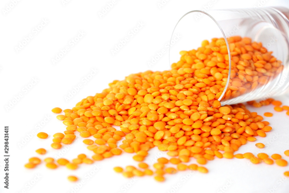 Red lentils on white background. Different forms of dry lentils. Lentils red in a transparent glass jar. Handful of legumes.
