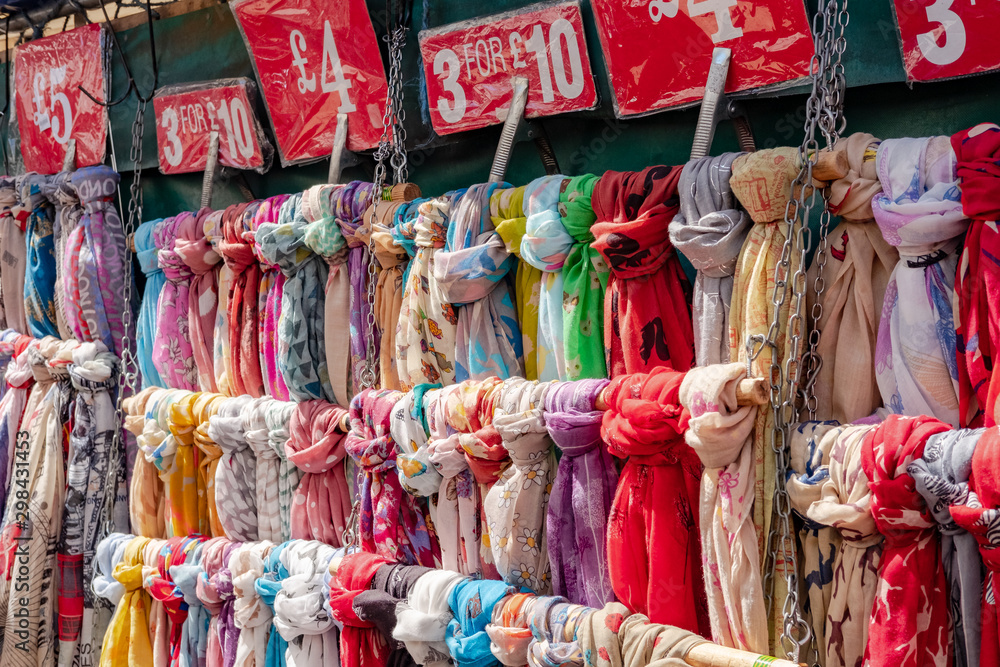 Close-up, shallow focus view of Women's neck scars on sale in an open market. Showing the large variety of designs and colours available to purchase.