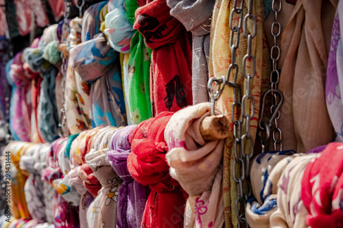 Close-up, shallow focus view of Women's neck scars on sale in an open market. Showing the large variety of designs and colours available to purchase.