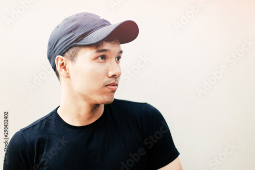 Young handsome asian men wearing casual black shirt and hat on white background in Sai Gon city, Vietnam © Olly