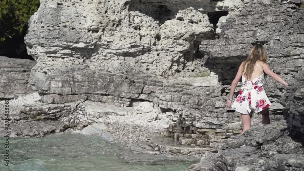young woman walking along a rocky shoreline. Long shot. young woman walking along a rocky shoreline. Long shot.