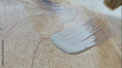 Painting the wooden surface with a colorless varnish Application of varnish on a wooden surface with a brush made of natural pile