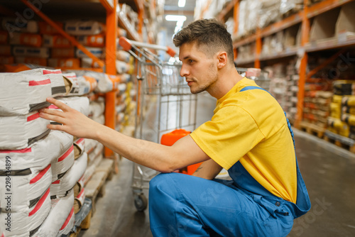 Male constructor choosing cement in hardware store