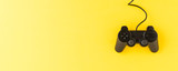 Black video game console on yellow background with copyspace. Top view. Banner