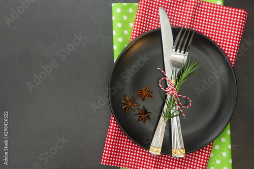 cChristmas place setting with ribbon. Black plate with fork and knife, decorated. Top view, copy space. photo