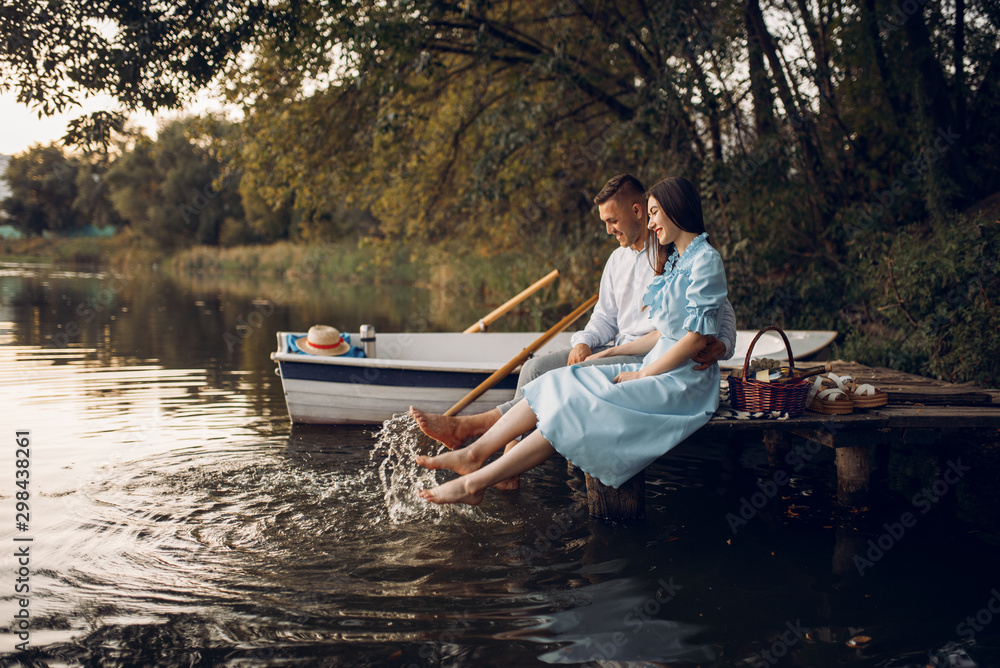Love couple sitting on the pier on quiet lake Love couple sitting on the pier on quiet lake